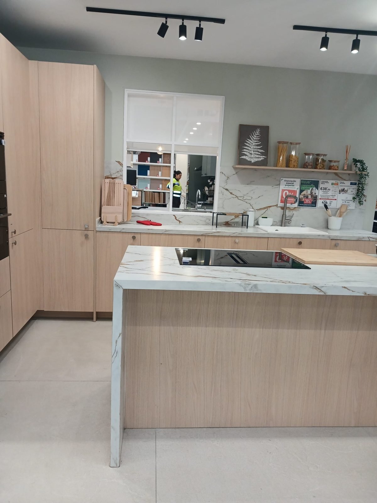 Cocina reformada con isla y encimera de mármol por Reformas Jiménez