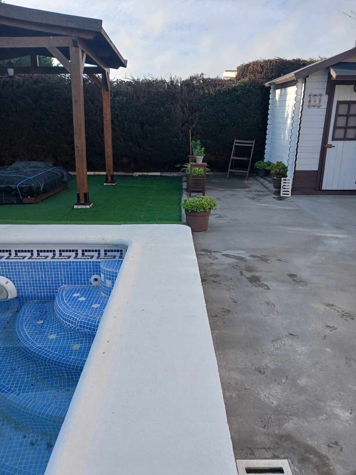 Jardín con piscina y césped reformado por Reformas Jiménez